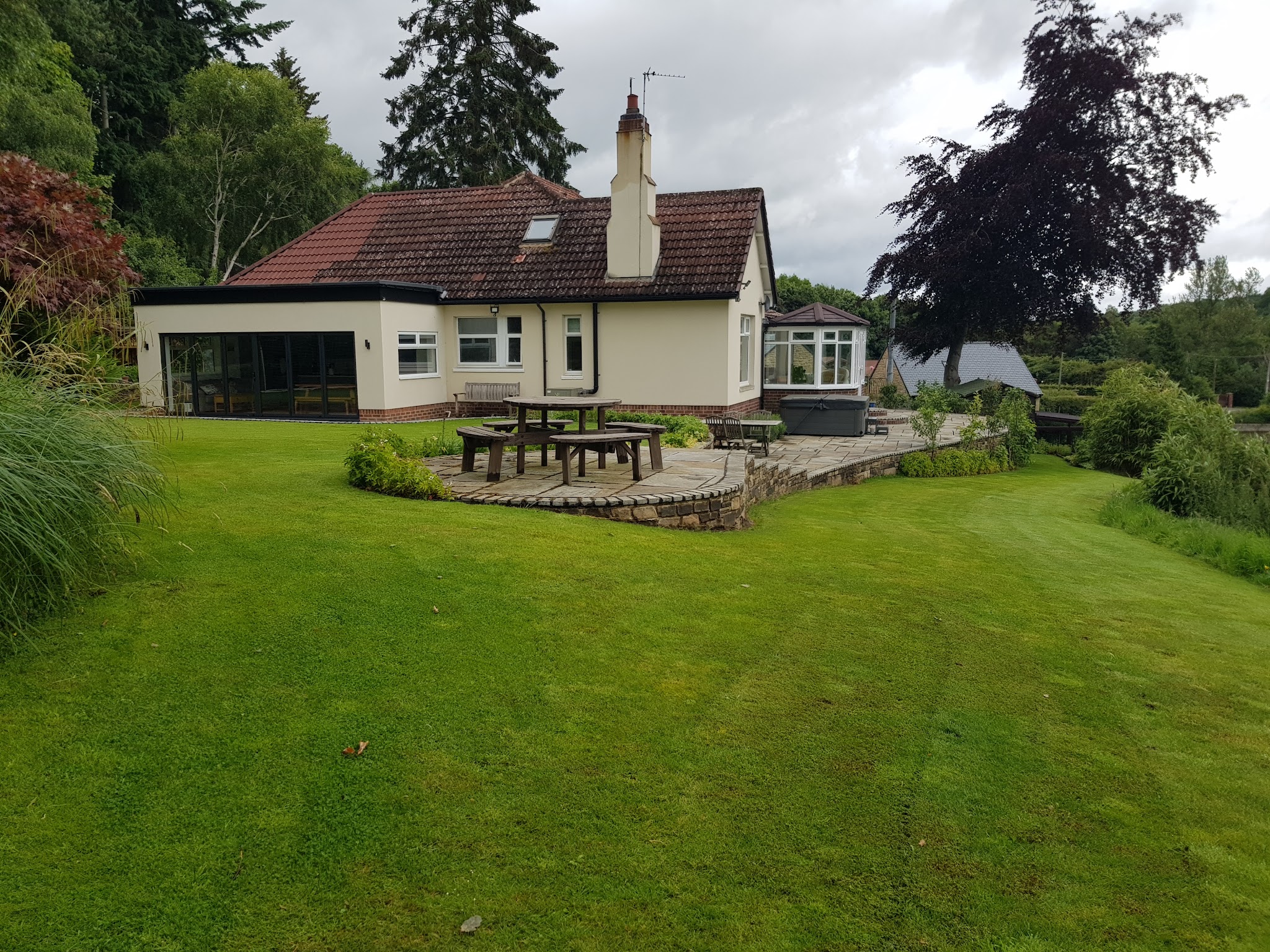 Bungalow extension with anthracite folding patio doors opening onto a lawn and stone patio